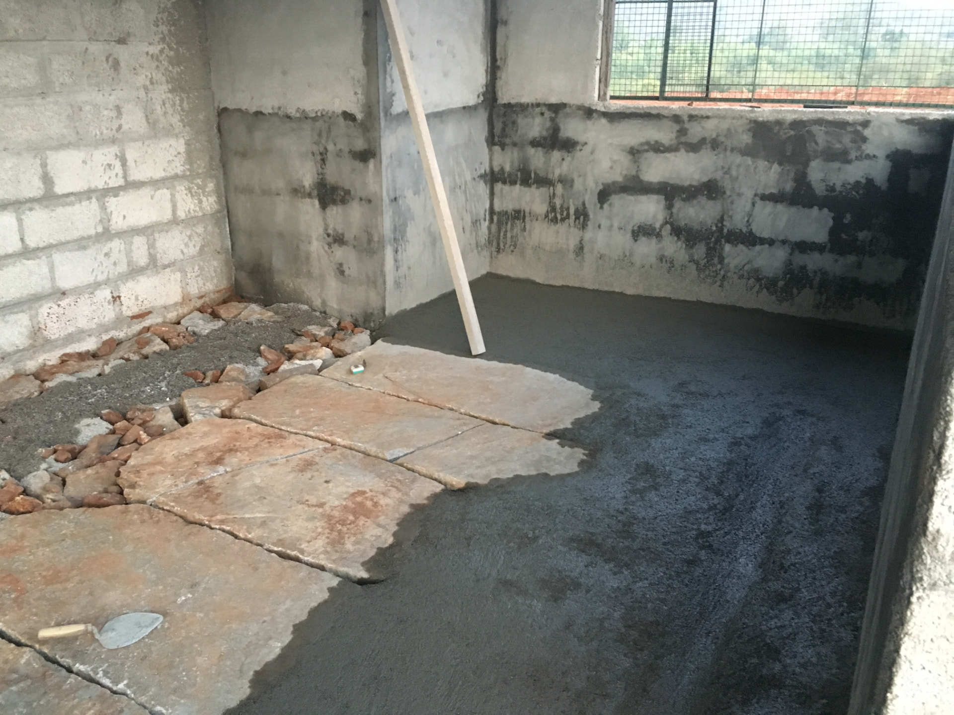 Wet concrete being laid over stone slabs inside the shed