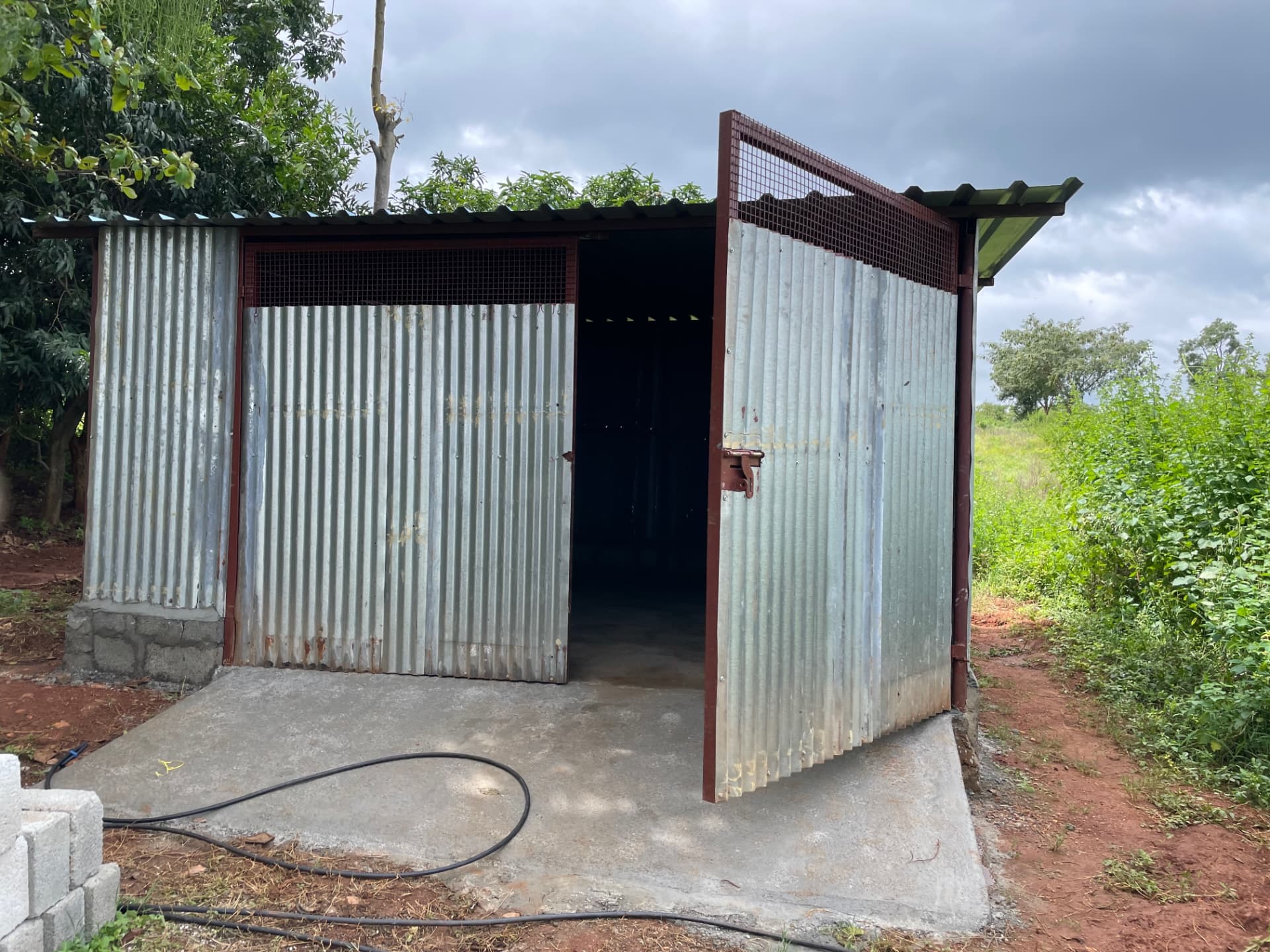 New tin sheet storage shed with concrete floor beside the field
